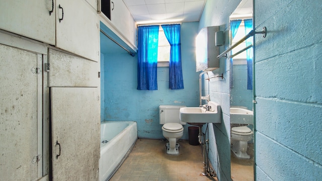 bathroom featuring sink, toilet, and a bath to relax in