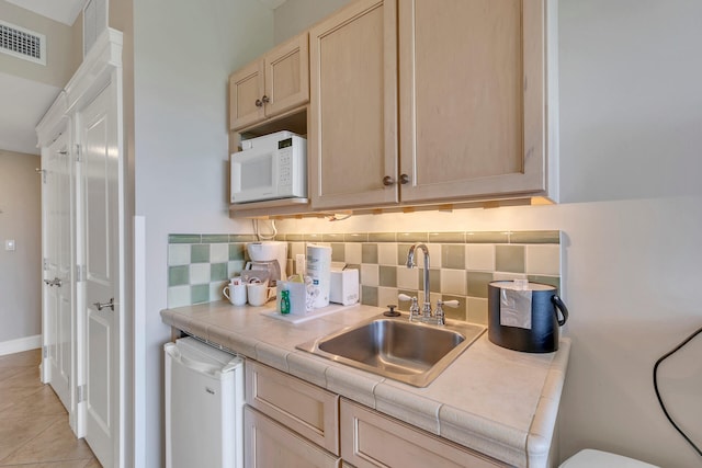 kitchen featuring light tile floors, sink, white appliances, tasteful backsplash, and tile countertops