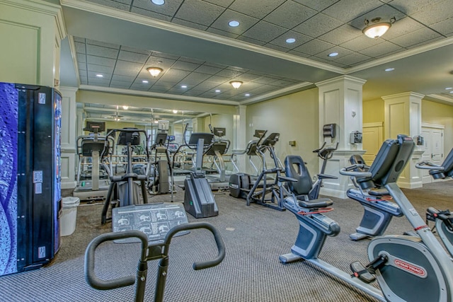 gym with a drop ceiling, decorative columns, crown molding, and carpet flooring