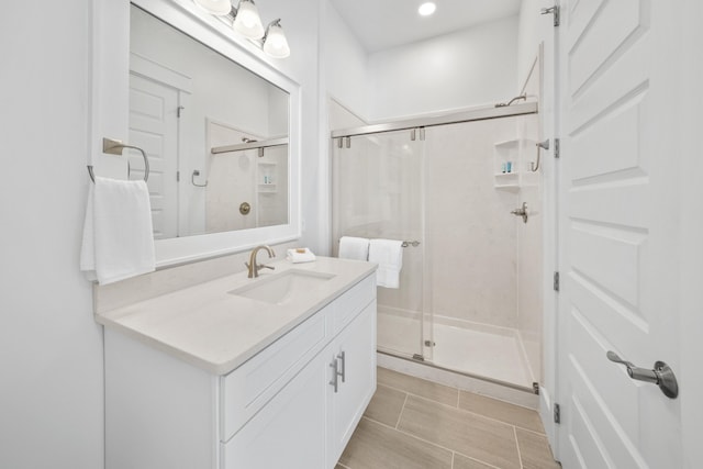 bathroom with a shower with door, vanity, and tile floors