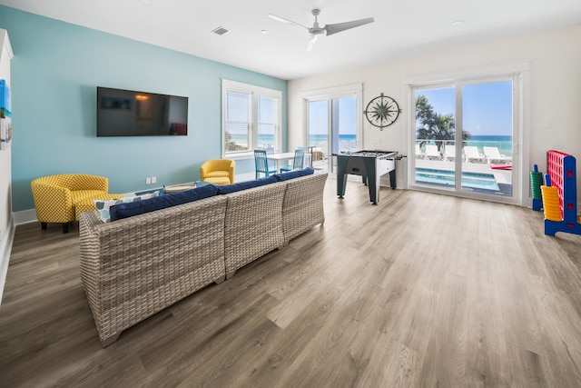 living room with wood-type flooring, a water view, and ceiling fan