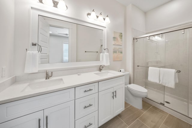 bathroom with double sink vanity, toilet, tile floors, and a shower with shower door