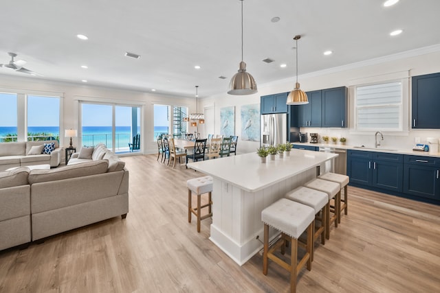 kitchen featuring a kitchen bar, a water view, light hardwood / wood-style flooring, sink, and a center island