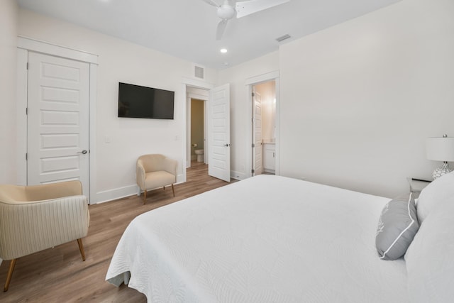 bedroom with hardwood / wood-style floors, ceiling fan, and connected bathroom