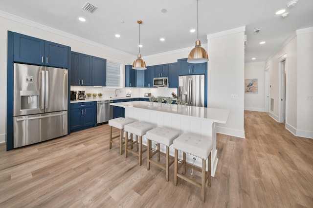 kitchen with pendant lighting, stainless steel appliances, blue cabinets, and light wood-type flooring