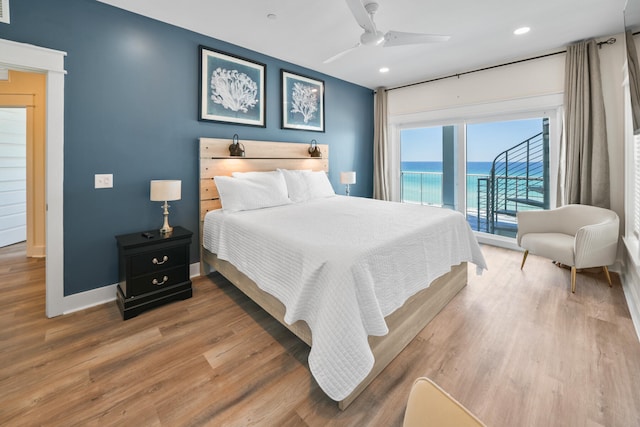 bedroom with ceiling fan, a water view, hardwood / wood-style flooring, and access to exterior