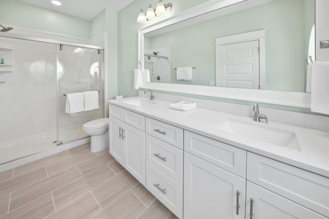 bathroom featuring a shower with door, toilet, tile floors, and dual vanity