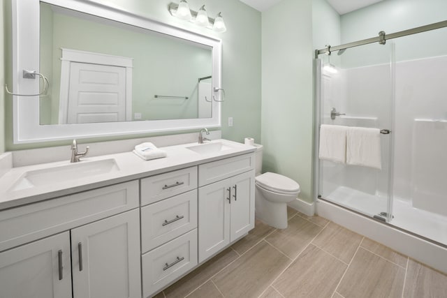 bathroom with tile flooring, double sink vanity, an enclosed shower, and toilet