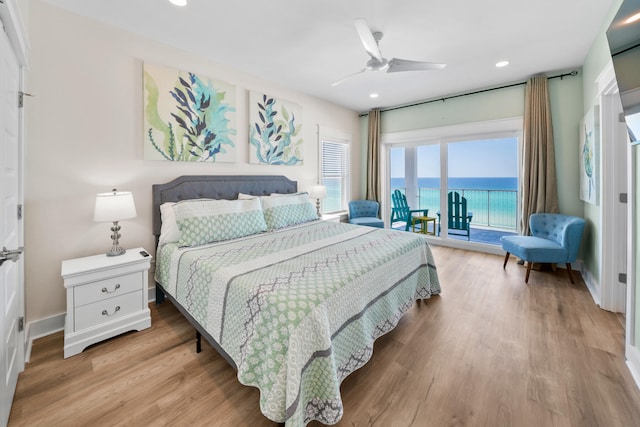 bedroom featuring hardwood / wood-style floors, ceiling fan, a water view, and access to exterior