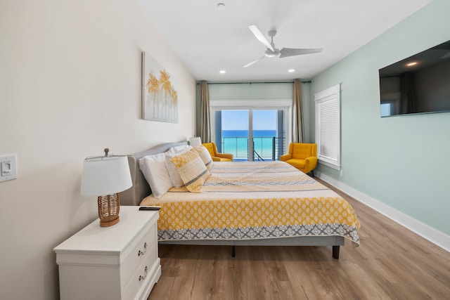 bedroom with wood-type flooring, ceiling fan, and a water view