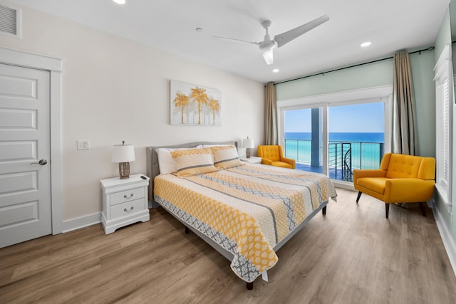 bedroom featuring light hardwood / wood-style flooring, a water view, and ceiling fan