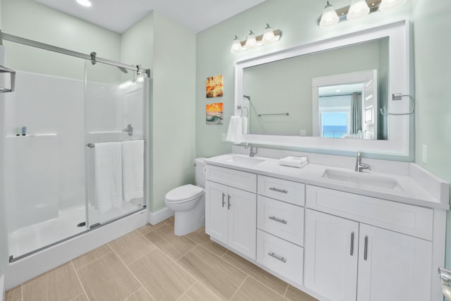 bathroom featuring large vanity, double sink, tile floors, toilet, and a shower with shower door