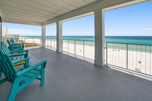 view of patio / terrace featuring a beach view, a water view, and a balcony