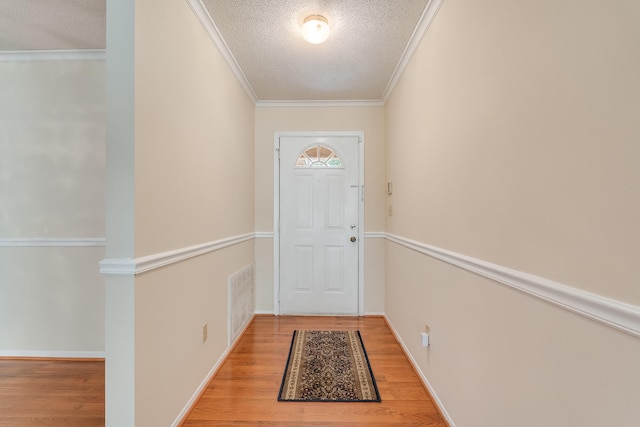 entryway featuring a textured ceiling, hardwood / wood-style floors, and crown molding