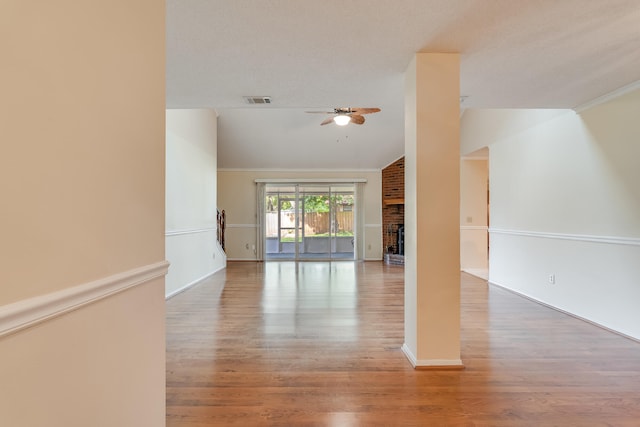 empty room with wood-type flooring, a brick fireplace, vaulted ceiling, ceiling fan, and a textured ceiling