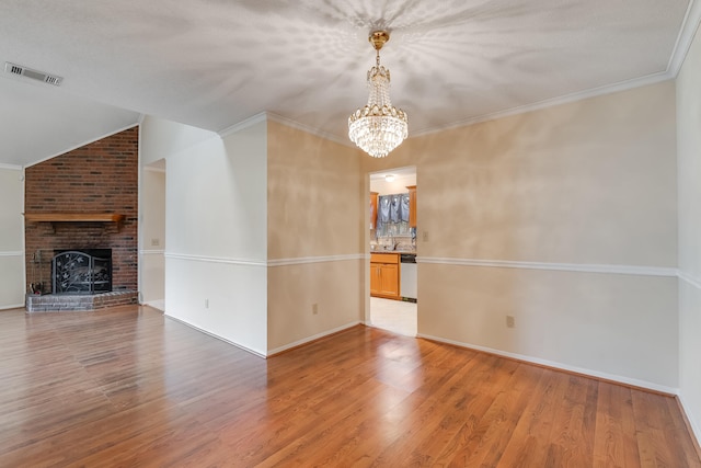 unfurnished living room featuring light hardwood / wood-style flooring, a fireplace, a notable chandelier, and ornamental molding