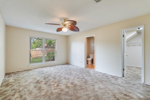 unfurnished bedroom with ceiling fan, a walk in closet, a closet, and carpet floors