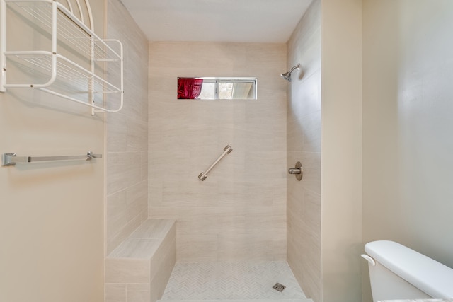 bathroom featuring tiled shower and toilet