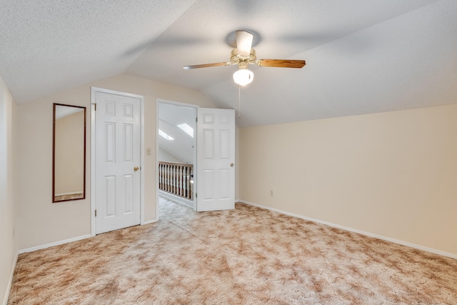 additional living space with lofted ceiling, ceiling fan, light carpet, and a textured ceiling