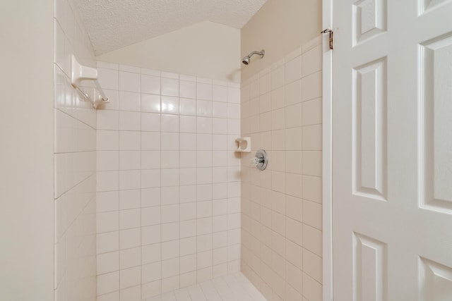 bathroom with a textured ceiling and a tile shower