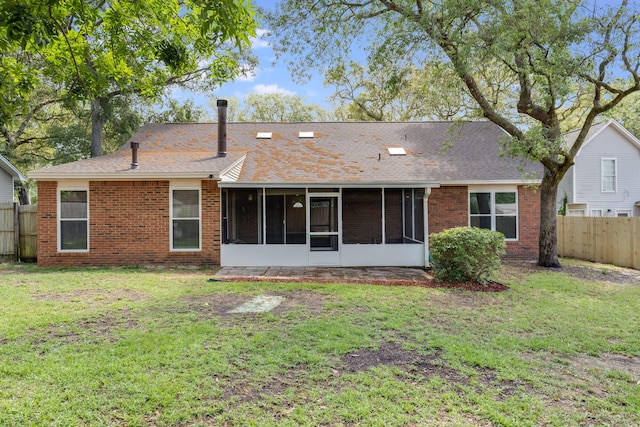 rear view of house featuring a sunroom and a lawn