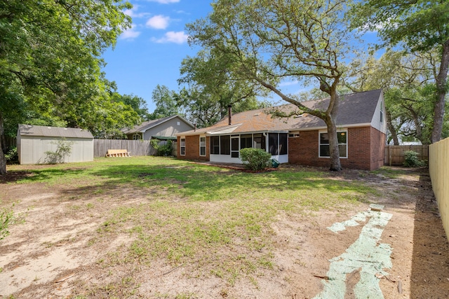 back of house featuring a yard, a shed, and a sunroom