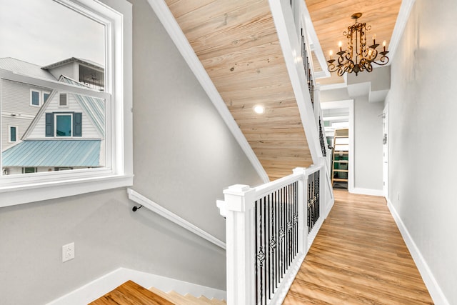 hall with a chandelier, ornamental molding, wooden ceiling, and hardwood / wood-style flooring