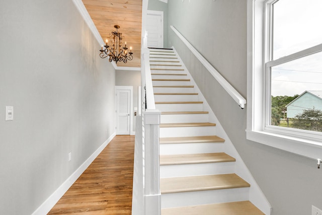 stairs with ornamental molding, a chandelier, and hardwood / wood-style flooring