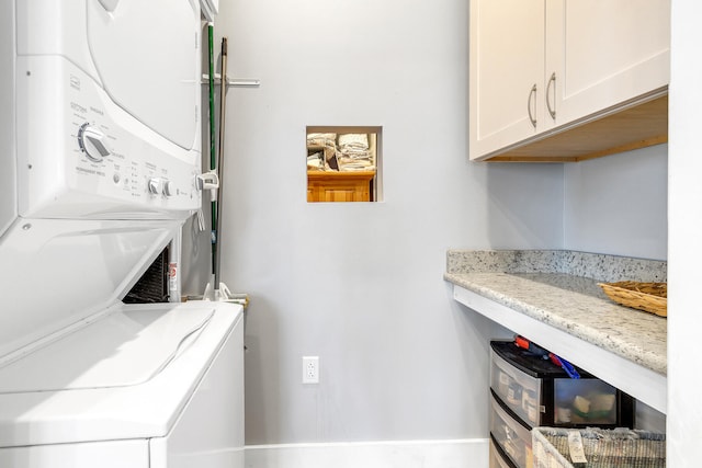 washroom featuring cabinets and stacked washer and clothes dryer