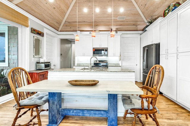 kitchen with pendant lighting, a kitchen island with sink, lofted ceiling, and appliances with stainless steel finishes