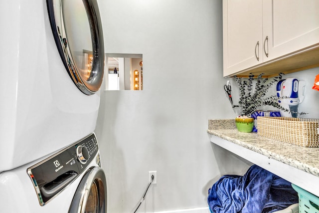 laundry area featuring cabinets and stacked washer / drying machine