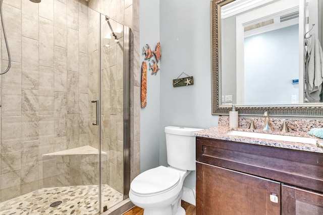 bathroom featuring wood-type flooring, vanity, toilet, and a shower with door