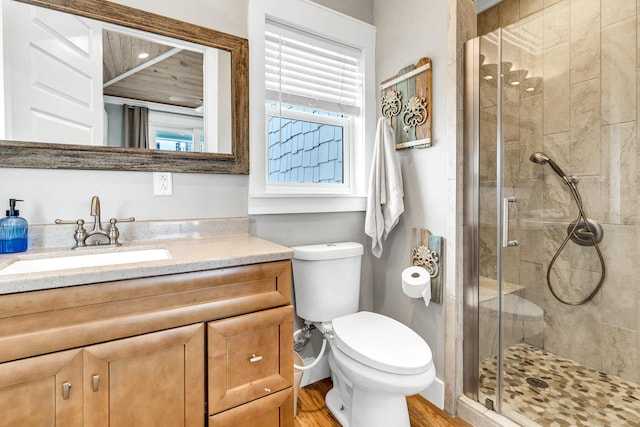 bathroom with hardwood / wood-style floors, vanity, toilet, and a shower with shower door