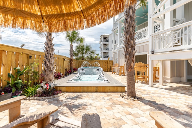 view of patio with an outdoor hot tub and a balcony