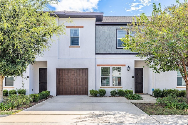 view of front of property featuring concrete driveway, an attached garage, and stucco siding