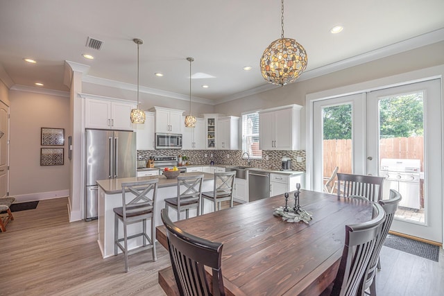 dining space featuring light wood finished floors, visible vents, and crown molding