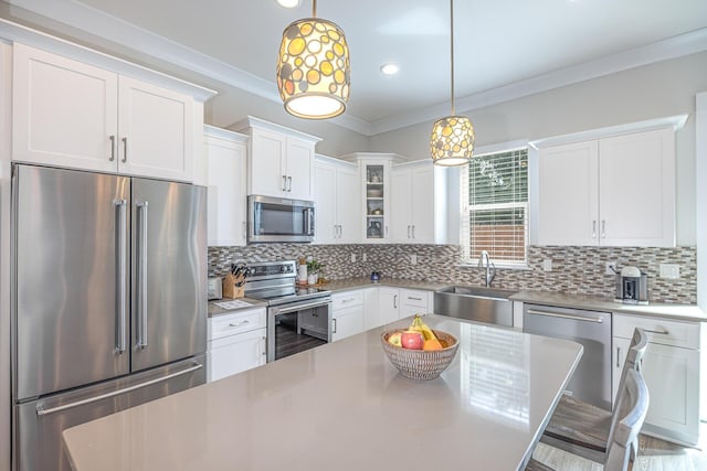 kitchen with stainless steel appliances, a sink, decorative backsplash, and ornamental molding