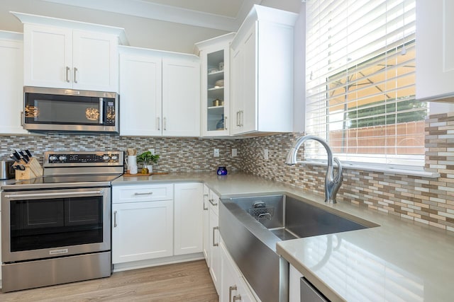 kitchen with white cabinets, decorative backsplash, stainless steel appliances, and light countertops