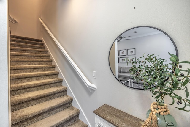 stairs featuring a ceiling fan