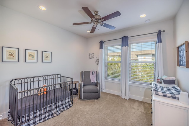 bedroom featuring a nursery area, light colored carpet, baseboards, and recessed lighting