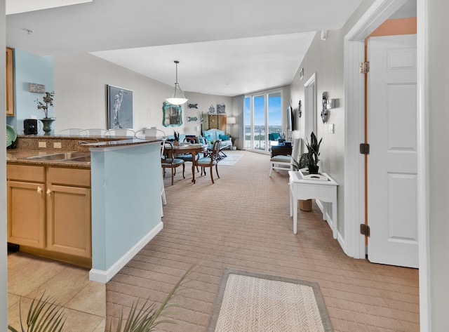 kitchen with light colored carpet, kitchen peninsula, pendant lighting, and dark stone counters