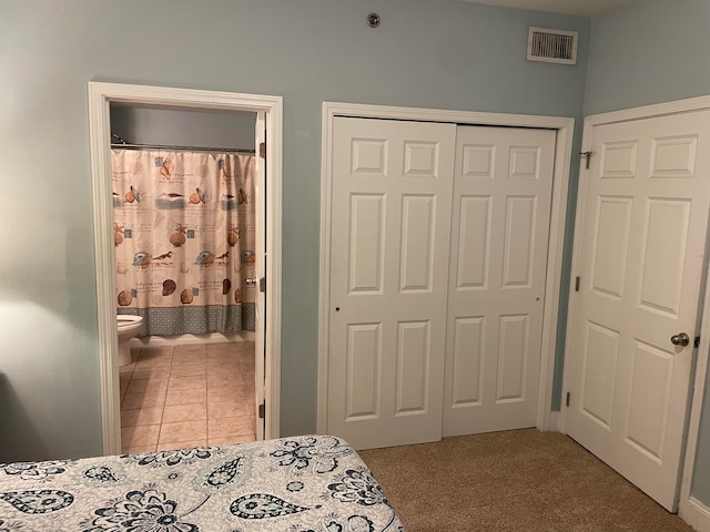 bedroom featuring ensuite bath and light colored carpet