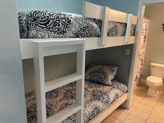 bedroom featuring light tile floors and ensuite bathroom