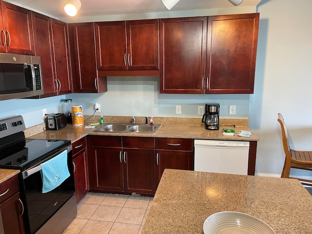 kitchen with light stone counters, stainless steel appliances, sink, and light tile flooring