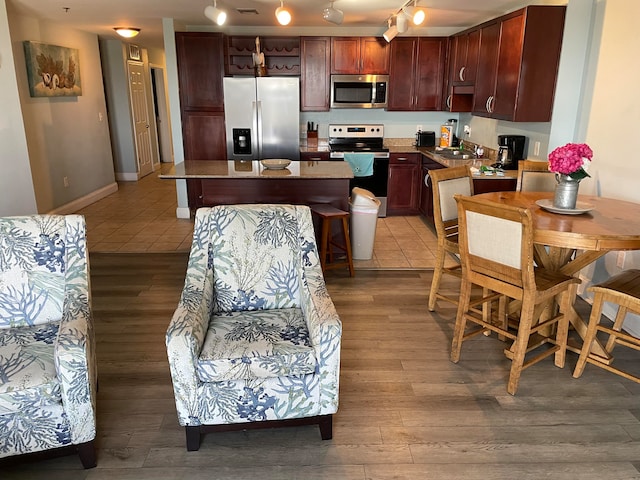 kitchen featuring stainless steel appliances, rail lighting, a kitchen breakfast bar, sink, and tile floors