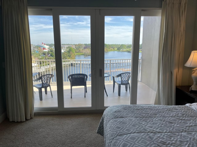 carpeted bedroom with a water view and french doors