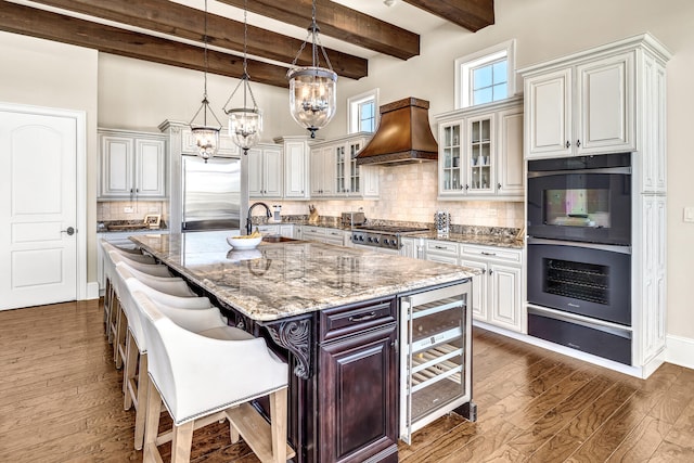 24 Norriego Rd, Destin, FL 32541 - kitchen with a kitchen island with sink, a breakfast bar, built in refrigerator, custom range hood, and tasteful backsplash