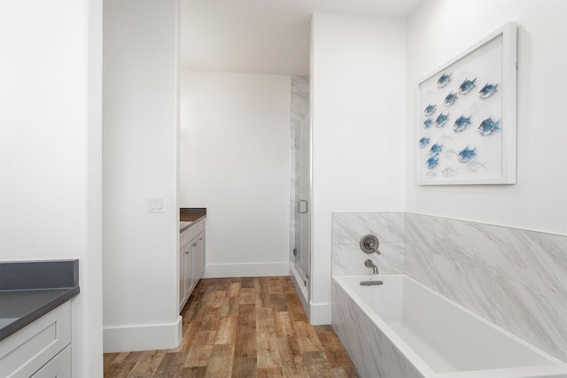 bathroom featuring vanity, hardwood / wood-style flooring, and plus walk in shower