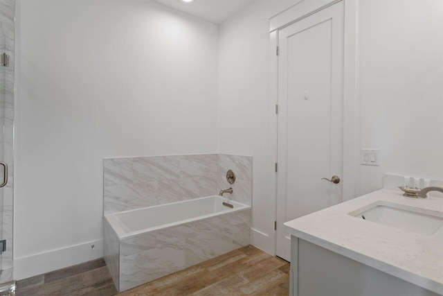 bathroom featuring tiled tub, vanity, and hardwood / wood-style flooring