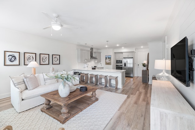 living room featuring sink, ceiling fan, and light hardwood / wood-style flooring